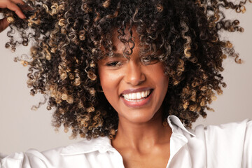 Portrait of joyful woman with afro hair smiling over white background. Isolated. - obrazy, fototapety, plakaty