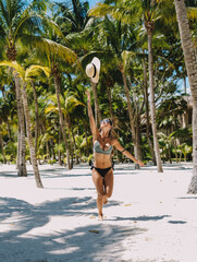 Modelo femenina posando en bikini en una playa paradisíca con palmeras