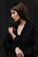 Portrait of a young brunette with long hair in the studio. Dramatic photo in dark colors.