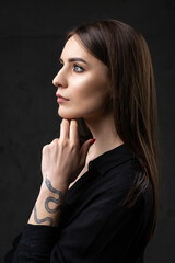 Portrait of a young brunette with long hair in the studio. Dramatic photo in dark colors.
