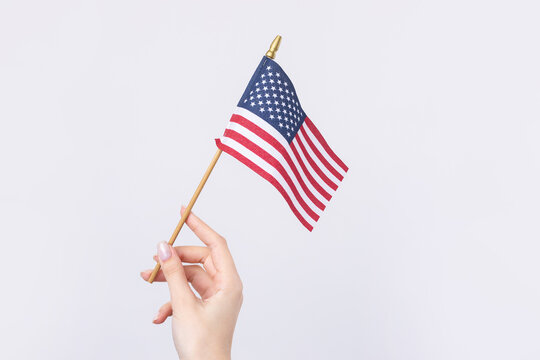 A beautiful female hand holds an American flag on a white background.