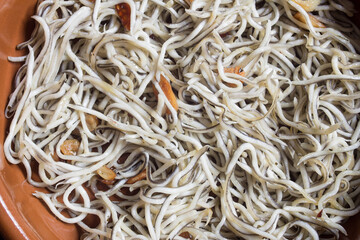 Overhead view of a traditional dish of spicy eels in garlic with prawns on a clay bowl. Textures and fish.