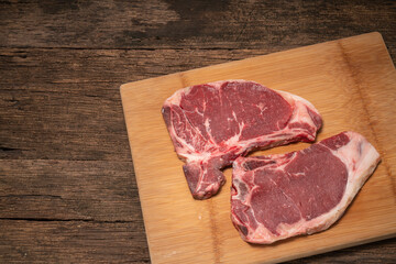 Raw fresh beef T-bone steak on wooden background, Close-up view of marble t-bone steak isolated on...
