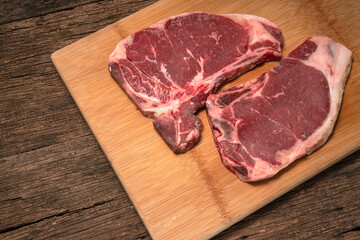 Raw fresh beef T-bone steak on wooden background, Close-up view of marble t-bone steak isolated on wooden background.