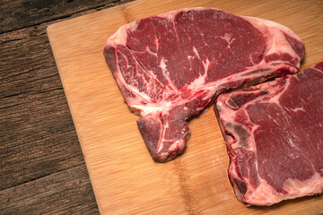 Raw fresh beef T-bone steak on wooden background, Close-up view of marble t-bone steak isolated on wooden background.