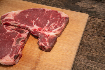 Raw fresh beef T-bone steak on wooden background, Close-up view of marble t-bone steak isolated on...