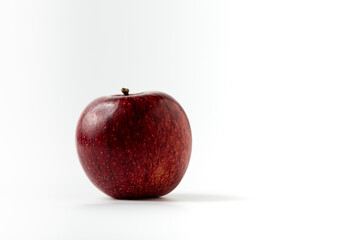 A maroon red organic apple on a plain white background. free work area