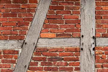 Background texture of an old timber frame wall, consisting of weathered wooden beams and red...