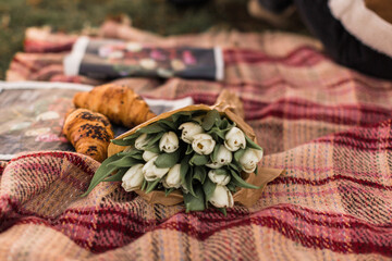 Top view of newspapper, flowers, tulips, croissants on a blanket background. Selective focus.
