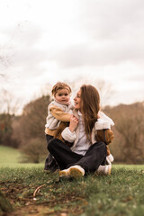 Happy mother with daughter sitting in  park on a grass...