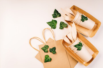 Eco craft paper tableware,cups,fast food containers.Recycling,eco-friendly concept.Disposable eco cutlery,plates,spoons,knives,forks on a light background.Craft paper bag for food delivery.Copy space.