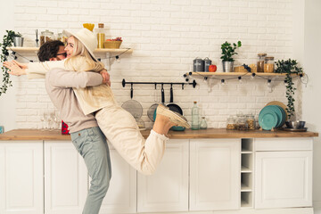 extremely happy caucasian long-haired blonde girlfriend is held up by her partner while celebrating...