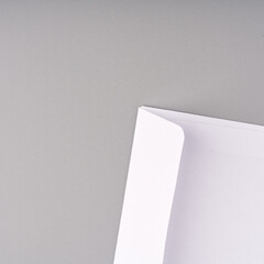 A white envelope on a gray background. Closeup. Top view.