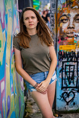 Young and beautiful woman leans against a colorful wall and poses for the camera - typical street style - travel photography