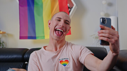 Funny non-binary European influencer person takes a selfie in front of a rainbow pride flag. High quality photo