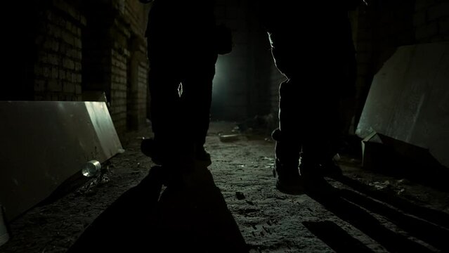 Group of armed men in camouflage carefully approach in corridor in light. A military group of men carefully walk towards the target at night in an abandoned facility High quality 4k footage
