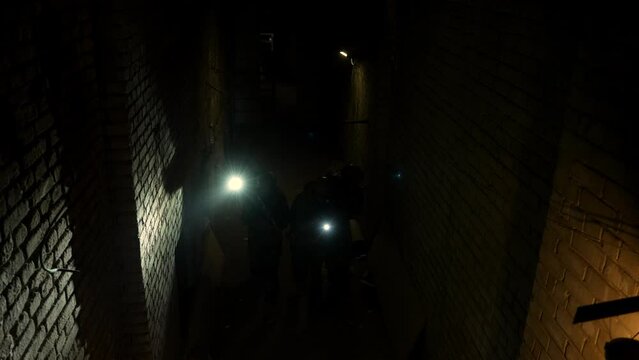 Group of armed men in camouflage carefully approach at night. A military group of men carefully walk towards the target at night in an abandoned facility High quality 4k footage