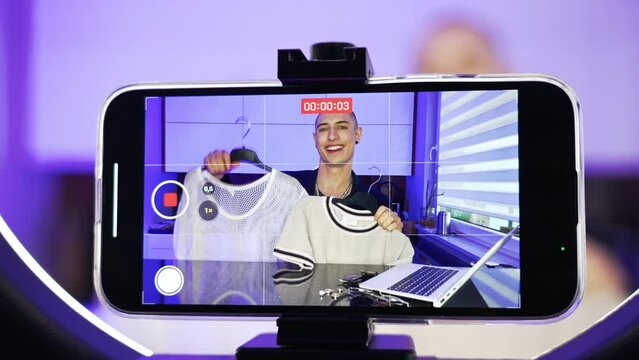 smartphone fashion haul made by a caucasian gay influencer who shows his mesh white t-shirts to the camera. High quality 4k footage
