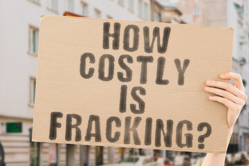 The question " How costly is fracking? " on a banner in men's hands with blurred background. Income. Profit. Revenue. Gain. Wealth. Earning. Budget. Action. Control. Currency. Fossil. Gasoline. Pump