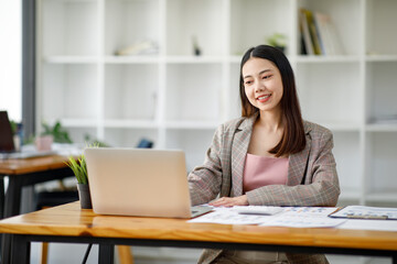 Asian young businesswoman working in the office with laptop computer, doing planning analyzing the financial report, business plan investment, finance analysis concept