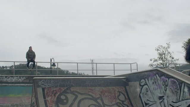 two males jump and spin at skatepark