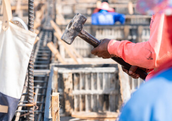 The worker used a hammer to hammer a piece of wood.