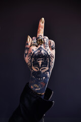 Tattooed attitude. Shot of a tattooed woman giving the finger to the camera.