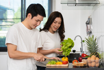 couple cutting vegetables for preparing healthy food in the kitchen at home