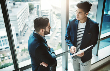 See, the data doesnt lie. Shot of two young businessmen discussing paperwork in a modern office.