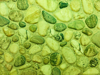 An old stone wall of green color with a stone texture. Green marble background with dark and light stones.
