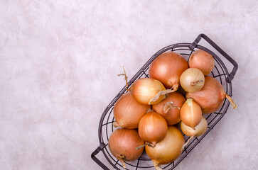 Fresh yellow onions in a metal basket