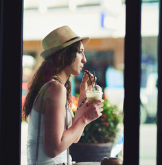 She prefers her caffeine chilled. Shot of a young woman enjoying a chilled coffee beverage while on vacation.