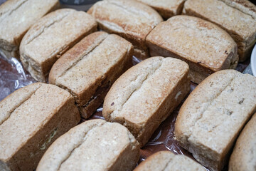 Pile of loaf toast bread freshly baked on table at the kitchen. Many traditional fresh round and square bread loaves for sale. No people. Selective focus.