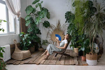 Stress relief after work from home. Relaxed young lady spend time in cozy indoor garden with...
