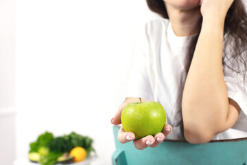 Close-up of a woman's hand holding an apple. The concept of spring and vitamins. Detox food. Front view.