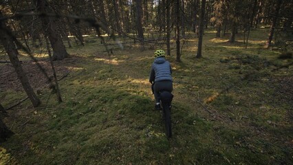 Obraz premium The woman travel on mixed terrain cycle touring with bike bikepacking outdoor. The traveler journey with bicycle bags. Stylish bikepacking, bike, sportswear in green black colors. Magic forest park.