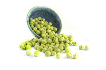 Freeze Dried Peas Spilling from Blue Pottery Bowl Isolated on White