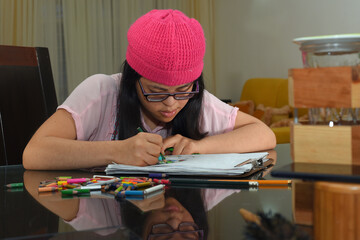 beautiful young woman with down syndrome sitting in the dining room of her house paints with colors...