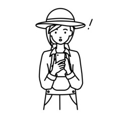 立ってスマートフォンを操作して何かに気づいて驚いた農家の女性