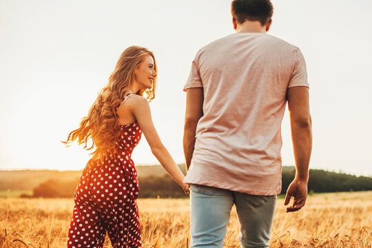 Newlywed couple running holding hands in wheat field. Family care. Holding hands. - Powered by Adobe