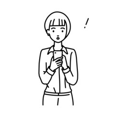 立ってスマートフォンを操作して何かに気づいて驚いたブラウスの女性