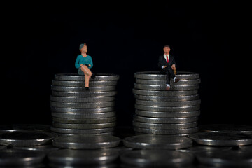 Miniature people sitting in the same height pile of coins Macro