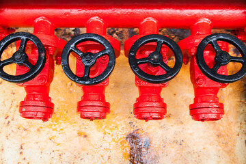 Four red fire hydrants on a fire line on a ship.