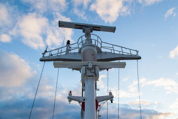 Mast of a cargo ship with navigation equipment bottom view. Radar, signal beeps and signal lights.