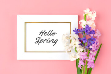 bouquet of spring flowers of lilac hyacinths, text Hello Spring on pink background Top view Flat lay Holiday card Hello spring concept