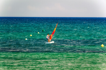 A person on surfboard sailing during summer day in Cambrils, Spain.