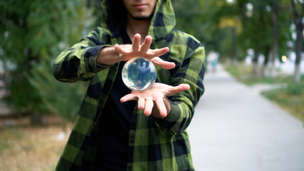 Artist shows trick with transparent sphere. Guy is engaged in juggling.