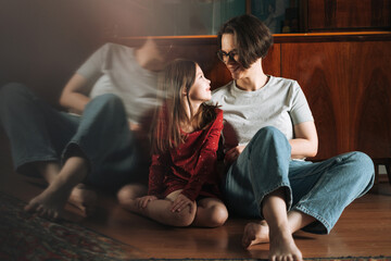 Fototapeta premium Tween girl and her mother sitting on the floor in living room at home