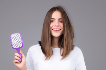 Girl combing hair. Beautiful young woman holding comb straightened hair.