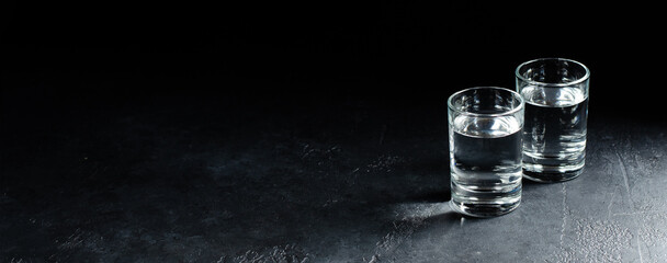 Glasses of vodka are in a row on dark background. Selective focus. Copy space